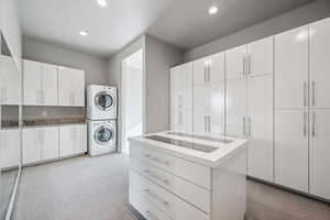 Laundry area featuring stacked washing machine and dryer, light carpet, and recessed lighting