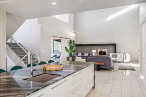 Kitchen featuring a towering ceiling, dark stone counters, white cabinets, light tile patterned flooring, and modern cabinets
