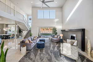 Living area featuring a ceiling fan, stairway, a towering ceiling, a fireplace, and recessed lighting
