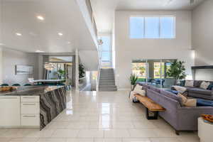 Living area with recessed lighting, a towering ceiling, and stairway