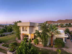 View of front of home with stucco siding and a yard