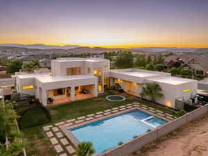 Rear view of house with stucco siding, a patio, a mountain view, a pool with connected hot tub, and a residential view