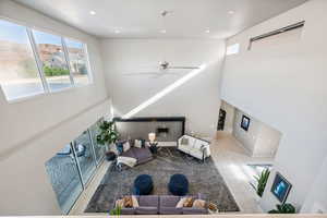 Tiled living room with a towering ceiling, recessed lighting, ceiling fan, and a glass covered fireplace