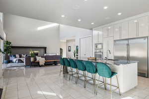 Kitchen with built in appliances, a kitchen bar, recessed lighting, modern cabinets, and white cabinets
