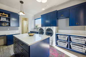 Laundry room featuring washer and clothes dryer, cabinet space, and light wood-style flooring