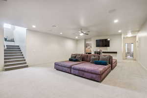 Carpeted living room featuring recessed lighting, stairs, and ceiling fan