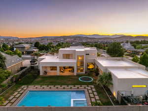 Back of house featuring a mountain view, stucco siding, a patio area, and a pool with connected hot tub