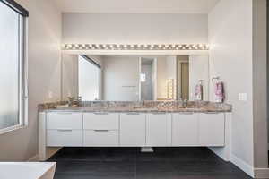 Bathroom with double vanity, tile patterned flooring, and a bathtub