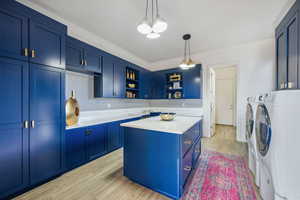 Kitchen featuring open shelves, independent washer and dryer, blue cabinets, and light countertops
