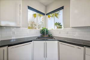 Kitchen with dishwasher, white cabinetry, and dark countertops