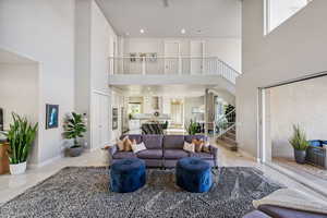 Living room featuring a high ceiling, stairway, and light tile patterned floors