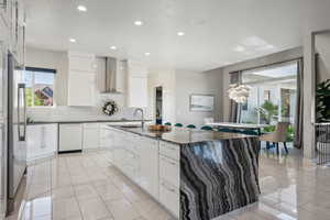 Kitchen featuring wall chimney exhaust hood, dishwasher, backsplash, recessed lighting, and white cabinetry