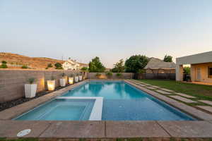 View of swimming pool featuring a fenced backyard and a pool with connected hot tub