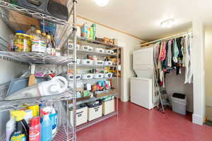 Storage room featuring stacked washer and clothes dryer