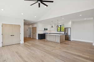 Kitchen with a center island, open floor plan, stainless steel appliances, light countertops, and recessed lighting
