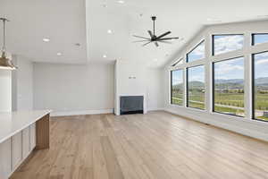 Unfurnished living room featuring light wood-style flooring, a ceiling fan, recessed lighting, and high vaulted ceiling