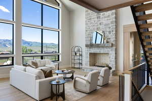 Living area with a towering ceiling, wood finished floors, a mountain view, and a stone fireplace