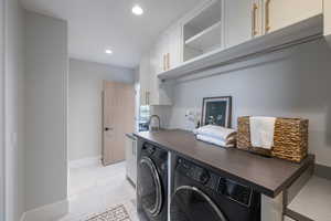 Washroom with washing machine and clothes dryer, cabinet space, recessed lighting, and light tile patterned floors
