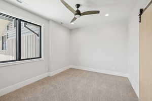 Spare room featuring a barn door, carpet, a ceiling fan, and recessed lighting