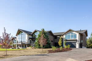 Contemporary house featuring asphalt driveway, an attached garage, and stone siding