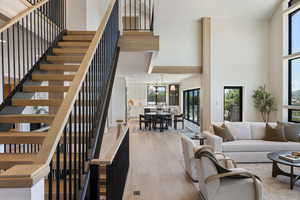Living area with hardwood / wood-style floors, stairs, and a towering ceiling