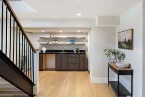 Indoor wet bar featuring light wood finished floors, recessed lighting, and stairs