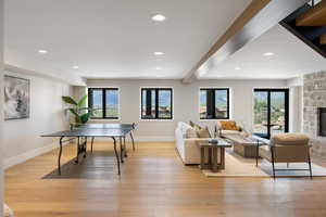 Playroom featuring light wood-style floors, beamed ceiling, recessed lighting, and a fireplace