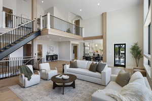 Living room featuring wood finished floors, recessed lighting, stairway, and a towering ceiling