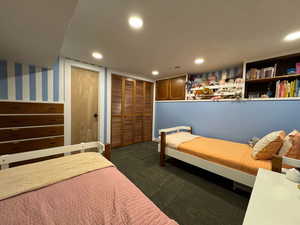 Bedroom with multiple closets, dark colored carpet, recessed lighting, and wallpapered walls