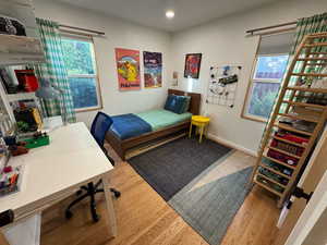 Bedroom with wood finished floors, a desk, and recessed lighting