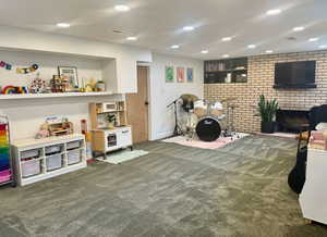 Game room featuring carpet, recessed lighting, brick wall, and a brick fireplace