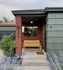 Property entrance featuring covered porch, brick siding, and a garage