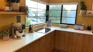 Kitchen with healthy amount of natural light, light countertops, brown cabinetry, and decorative backsplash