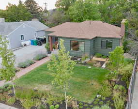 View of front of house featuring a chimney, a shingled roof, and a front yard