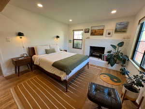 Bedroom featuring multiple windows, wood finished floors, recessed lighting, and a brick fireplace