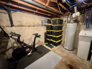 Unfinished basement with a water softener system and gas water heater
