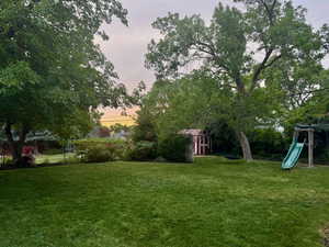 Yard at dusk featuring a playground and a storage shed
