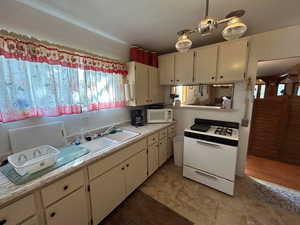 Kitchen featuring white appliances, light countertops, and white cabinets