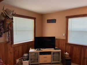 Living room featuring wooden walls, wainscoting, and baseboard heating