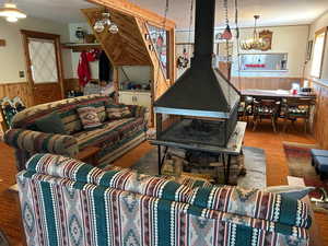 Living area with a wainscoted wall, a wood stove, wood walls, and a chandelier