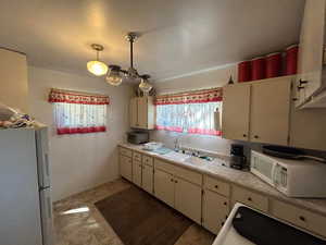 Kitchen featuring white appliances, light countertops, and white cabinetry