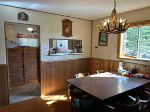 Dining space with a chandelier and wooden walls