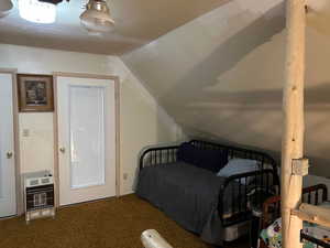 Carpeted bedroom featuring heating unit and vaulted ceiling