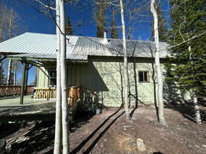 View of side of property with a wooden deck and a metal roof