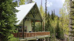 Back of property with a metal roof, a wooden deck, and a view of trees