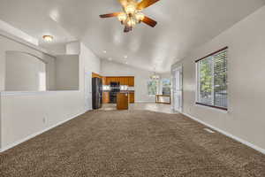 Unfurnished living room featuring vaulted ceiling, a chandelier, ceiling fan, light carpet, and recessed lighting