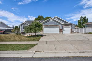 View of front of property featuring an attached garage, concrete driveway, and brick siding