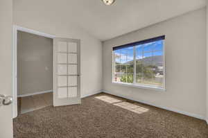 Spare room featuring carpet floors and lofted ceiling