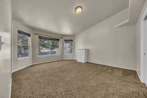 Empty room featuring carpet floors and vaulted ceiling