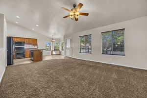 Kitchen with open floor plan, range with two ovens, freestanding refrigerator, a chandelier, and lofted ceiling